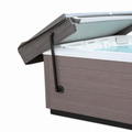 Black cover-lifter arm attached to a grey hot tub, supporting a partially raised folding cover